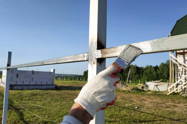 Arbetaren målar profilen för ett metall staket efter svetsning. — Stockfoto
