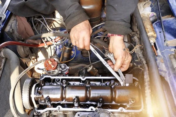 De meester in de garage tikt de kleppen in de oude auto, Vaz auto, een oude versleten auto. — Stockfoto