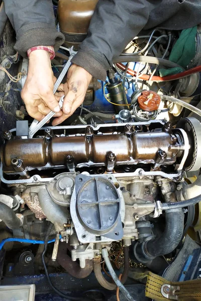 The master in the garage taps the valves in the old car, VAZ car, an old worn-out car.