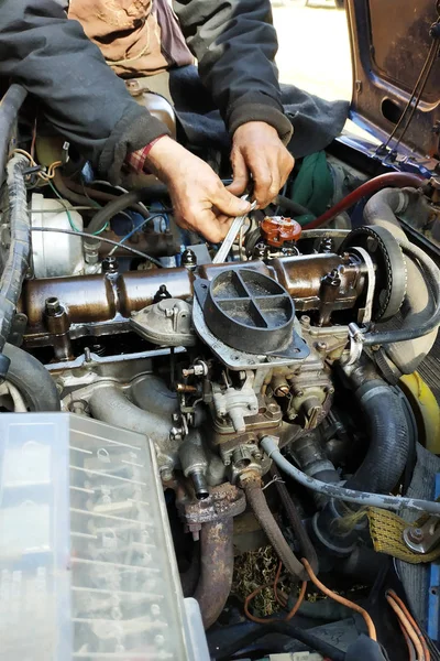 O mestre na garagem bate as válvulas no carro velho, carro VAZ, um carro velho desgastado . — Fotografia de Stock