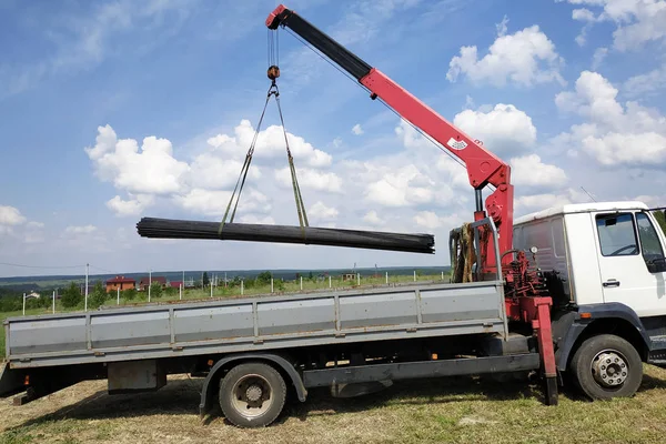 The truck crane in the field on the private land unloads the metal profile. — Stock Photo, Image