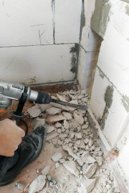 Bir perforatör ile bir işçi elektrik telleri yürütmek için evin duvar ve temel tatili.