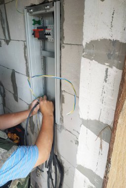 Profesyonel bir elektrikçi bir güç kalkanı için bir elektrik teli katıldı.