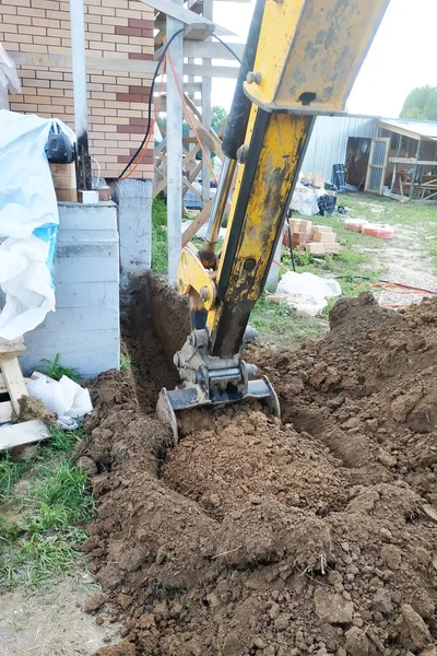 A escavadora cava uma pequena trincheira no quintal . — Fotografia de Stock