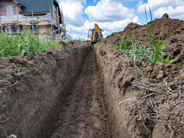 Excavadora de construcción excavando una ranura poco profunda para cableado eléctrico o cable . — Foto de Stock