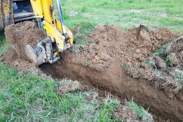 İnşaat ekskavatör kazma elektrik kablolama veya kablo için sığ bir oluk kazma. — Stok fotoğraf