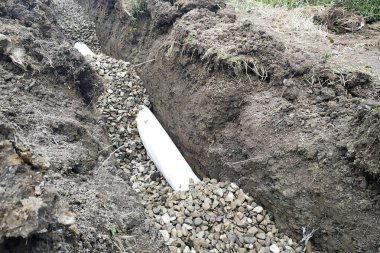 İşçiler evin etrafında su drenaj için drenaj işleri yürütmek.