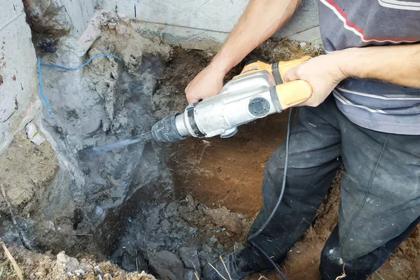 Trabalhador da indústria da construção civil usando broca de martelo pneumático para cortar a parede de tijolo de concreto, de perto — Fotografia de Stock