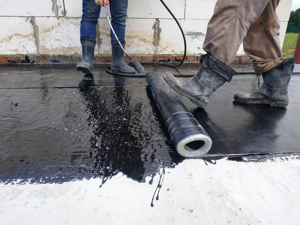 Worker covered surface, bitumen primer for improving adhesion during surfacing, rolled waterproofing, during the installation of isolation on industrial or household objects. — Stock Photo, Image