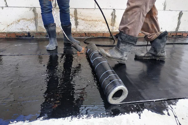 The workers cover the concrete screed with bituminous liquid solution and stele the waterproofing. — Stock Photo, Image