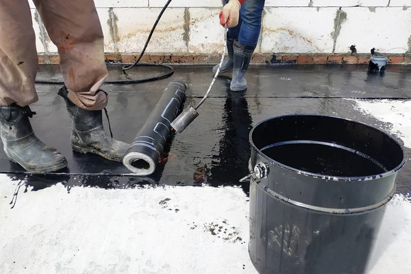 Los trabajadores cubren la solera de hormigón con solución líquida bituminosa y estela la impermeabilización . — Foto de Stock
