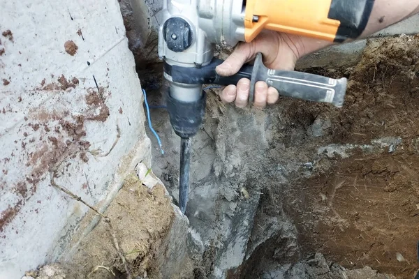 Operaio edile utilizzando trapano pneumatico martello per tagliare il mattone di cemento muro, primo piano — Foto Stock