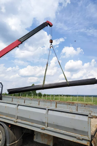 The truck crane in the field on the private land unloads the metal profile. — Stock Photo, Image