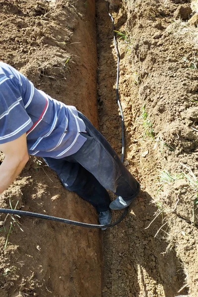 Θέτοντας ένα ηλεκτρικό καλώδιο στη γη ενός κύριου Ηλεκτρολόγου. — Φωτογραφία Αρχείου