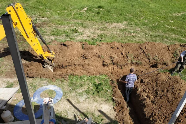 La excavadora cava una zanja para colocar el cable eléctrico . —  Fotos de Stock