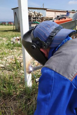 Şantiyede köyde, bir kaynakçı bir çit kaynak.