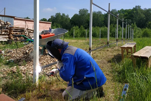 Bir çit montajcı yeni bir çit sonrası bir metal profil kaynak.