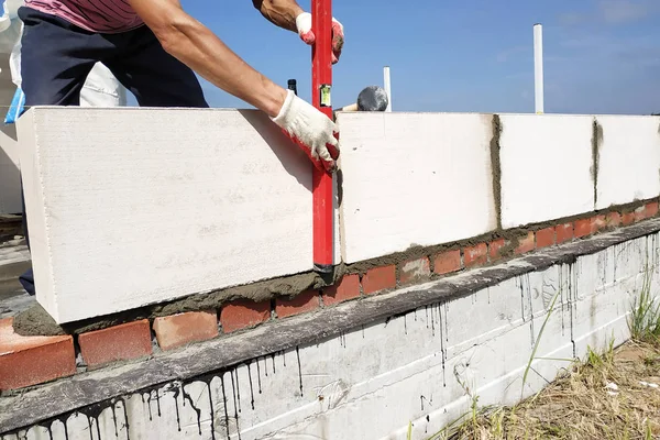 The worker measures the work out wall with a level.