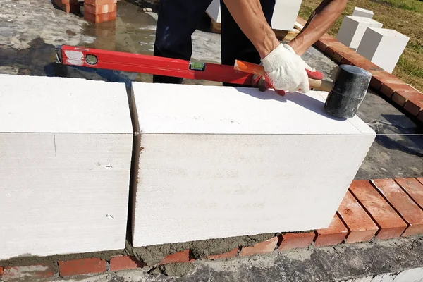 De meester gebruikt het niveau in de bouw en het metselwerk van het huis op het platteland. — Stockfoto