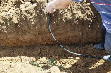 Usta bir elektrikçinin arazisine elektrik kablosu döşemek.