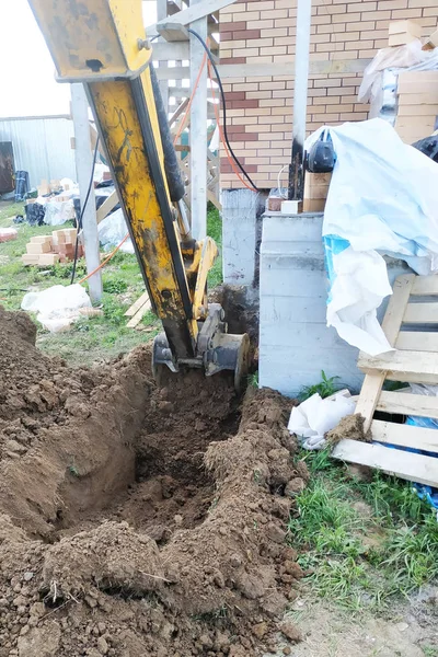 Penggali menggali parit dekat rumah kabel untuk ember kecil . — Stok Foto