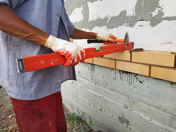 The master after laying the level to the brick, looks at the level horizontally.