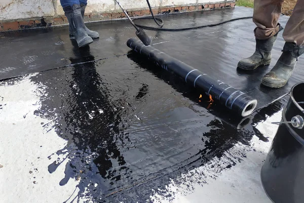 Los trabajadores cubren la solera de hormigón con solución líquida bituminosa y estela la impermeabilización . — Foto de Stock