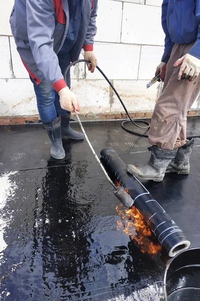 The master works with the assistant to work on the waterproofing of the surface.