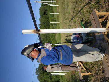 Koruyucu maske işçi kaynak çelik korkuluklar açık havada, kıvılcımlar gökyüzü ve alan arka plan karşı, aşağı sinek.
