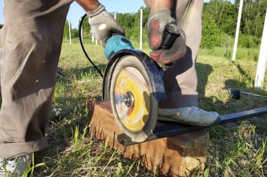 Bir açı değirmeni işçisi dışında bir metal profil keser.