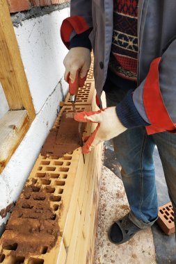 Yaz günü usta kırmızı tuğladan yapılmış evin ön cephesini inşa eder..
