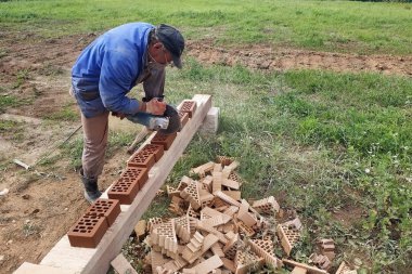 İşçi kırsal bir ön cephe tuğla ile bir köşe tuğla keser.