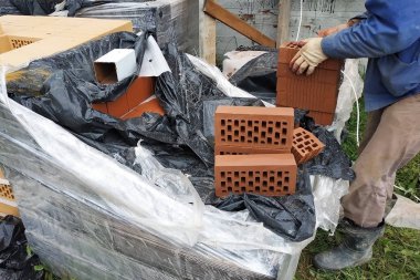 İşçi inşaat için daha fazla ölçüm ve kırpma için cephe tuğla çevirir.