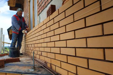 Usta, bir evin duvarını ön tuğladan inşa eder..