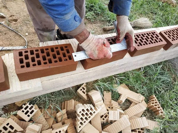 İşçi inşaat için daha fazla ölçüm ve kırpma için cephe tuğla çevirir.