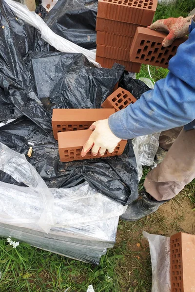 İşçi inşaat için daha fazla ölçüm ve kırpma için cephe tuğla çevirir.