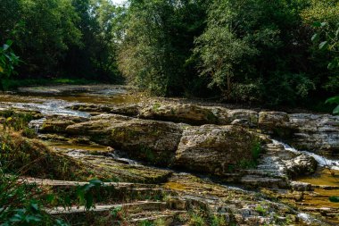 Su gövdesiküçük yosun adaları ile taşlarla çevrili yüksek dağ alanında güçlü su akışı.