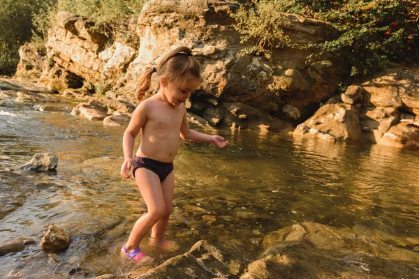 Kis aranyos szép lány úszik egy hegyi folyón. — Stock Fotó