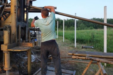 İşçiler özel alanda su üzerinde kuyular matkap, kurulum araç üzerine monte edilir.