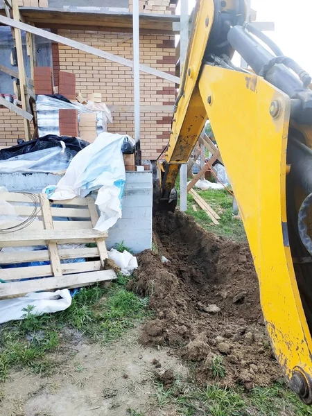 Penggali menggali parit dekat rumah kabel untuk ember kecil . — Stok Foto
