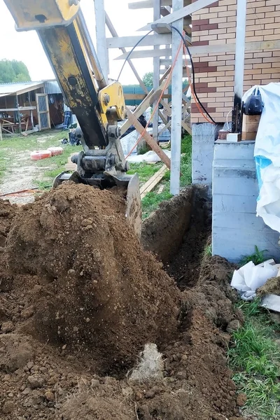 A escavadora cava uma pequena trincheira no quintal . — Fotografia de Stock