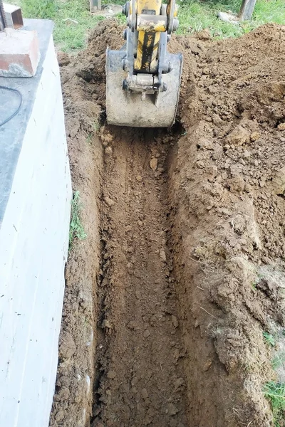 A escavadora cava uma pequena trincheira no quintal . — Fotografia de Stock