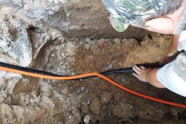 İş adamı, elektrik kablosunu hendek içinde kalkanı.