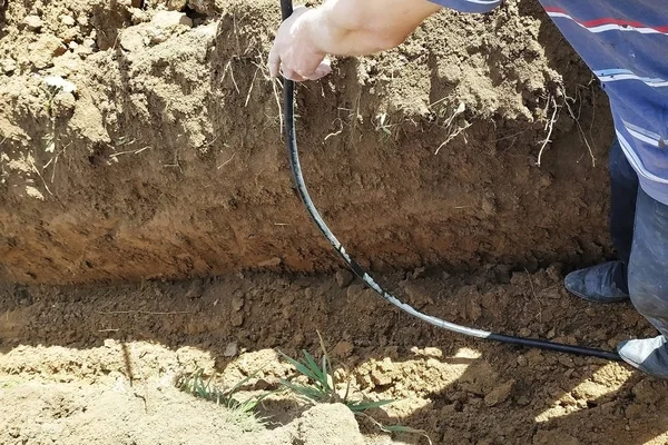 Posa di un cavo elettrico nel terreno di un maestro elettricista . — Foto Stock