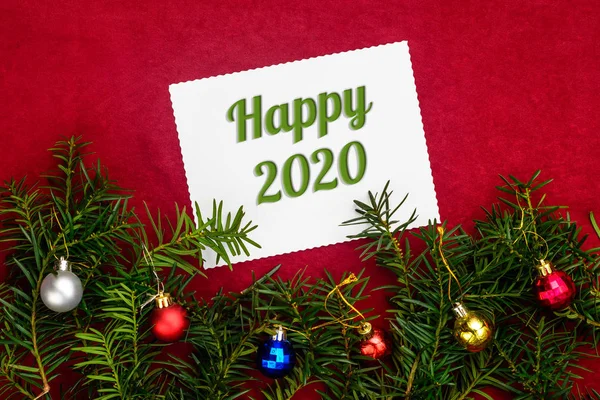 Composição de Natal e Ano Novo com números 2020 e ramos de árvore de Natal com bolas no fundo vermelho com vista superior — Fotografia de Stock