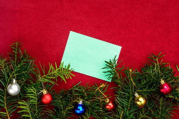 Darab papírt karácsonyi kíván egy piros háttér ágai karácsonyfa és a karácsonyi bálok. — Stock Fotó