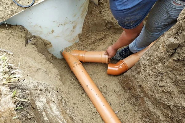 L'entrepreneur installe un égout dans un fossé et conduit le tuyau au puisard . — Photo