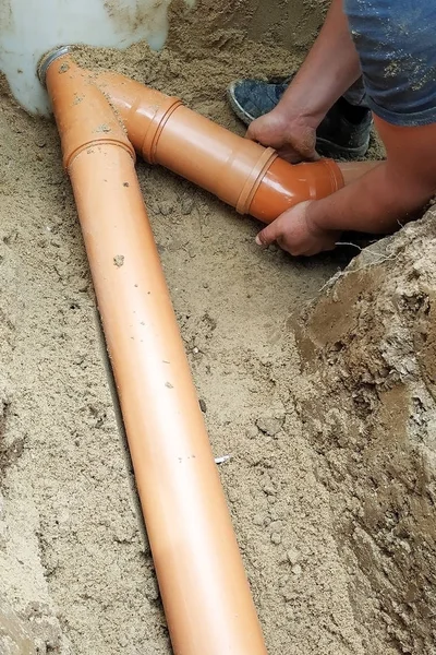 Um serralheiro fornece um tubo de esgoto para a fossa . — Fotografia de Stock