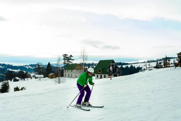 Junger Mann in grüner Jacke und lila Hose beim Skifahren. — Stockfoto