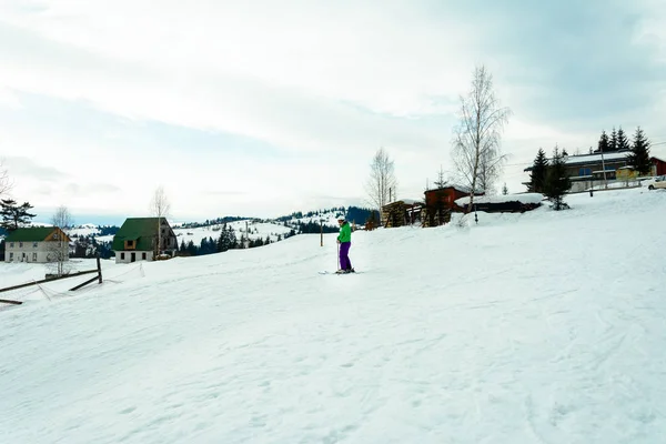 Joven con chaqueta verde y pantalones morados esquiando . — Foto de Stock